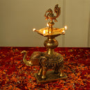 Brass peacock parrot Diya - exquisitely crafted brass oil lamp in the shape of a peacock with parrot motifs, golden finish, decorative home accent, fusion of elegance and vibrancy, traditional Indian Diya, emits a captivating and auspicious glow, perfect for festive occasions and religious ceremonies, enhances spiritual ambiance and decor with a touch of artistic brilliance.