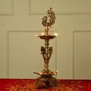 Brass peacock parrot Diya - exquisitely crafted brass oil lamp in the shape of a peacock with parrot motifs, golden finish, decorative home accent, fusion of elegance and vibrancy, traditional Indian Diya, emits a captivating and auspicious glow, perfect for festive occasions and religious ceremonies, enhances spiritual ambiance and decor with a touch of artistic brilliance.